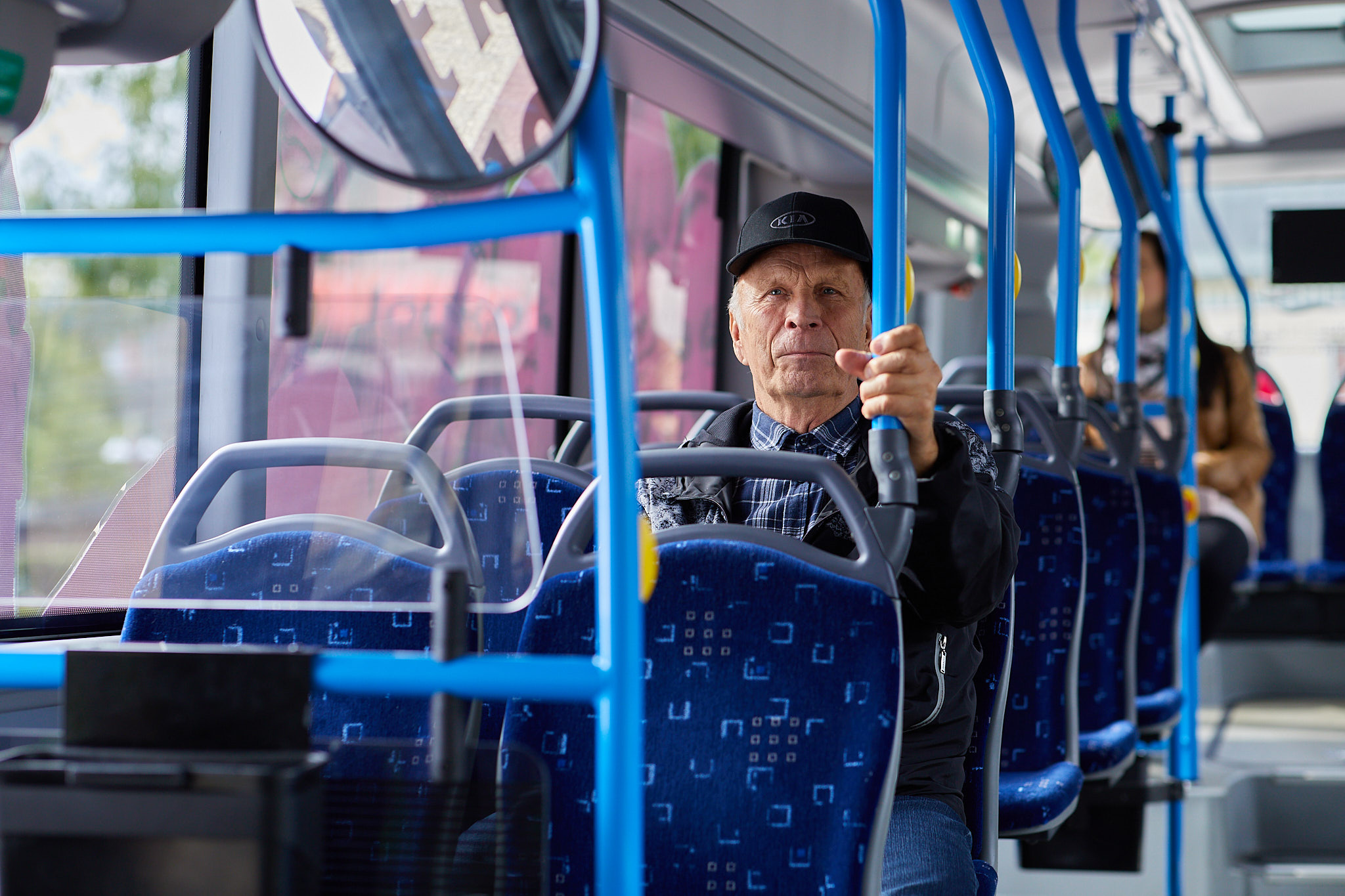 Vanha mies istumassa bussin penkillä.