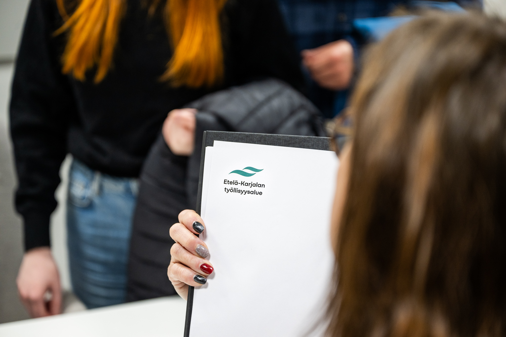 Kaksi henkilöä asiointitilanteessa. Paperi, jossa lukee Etelä-Karjalan työllisyysalue.