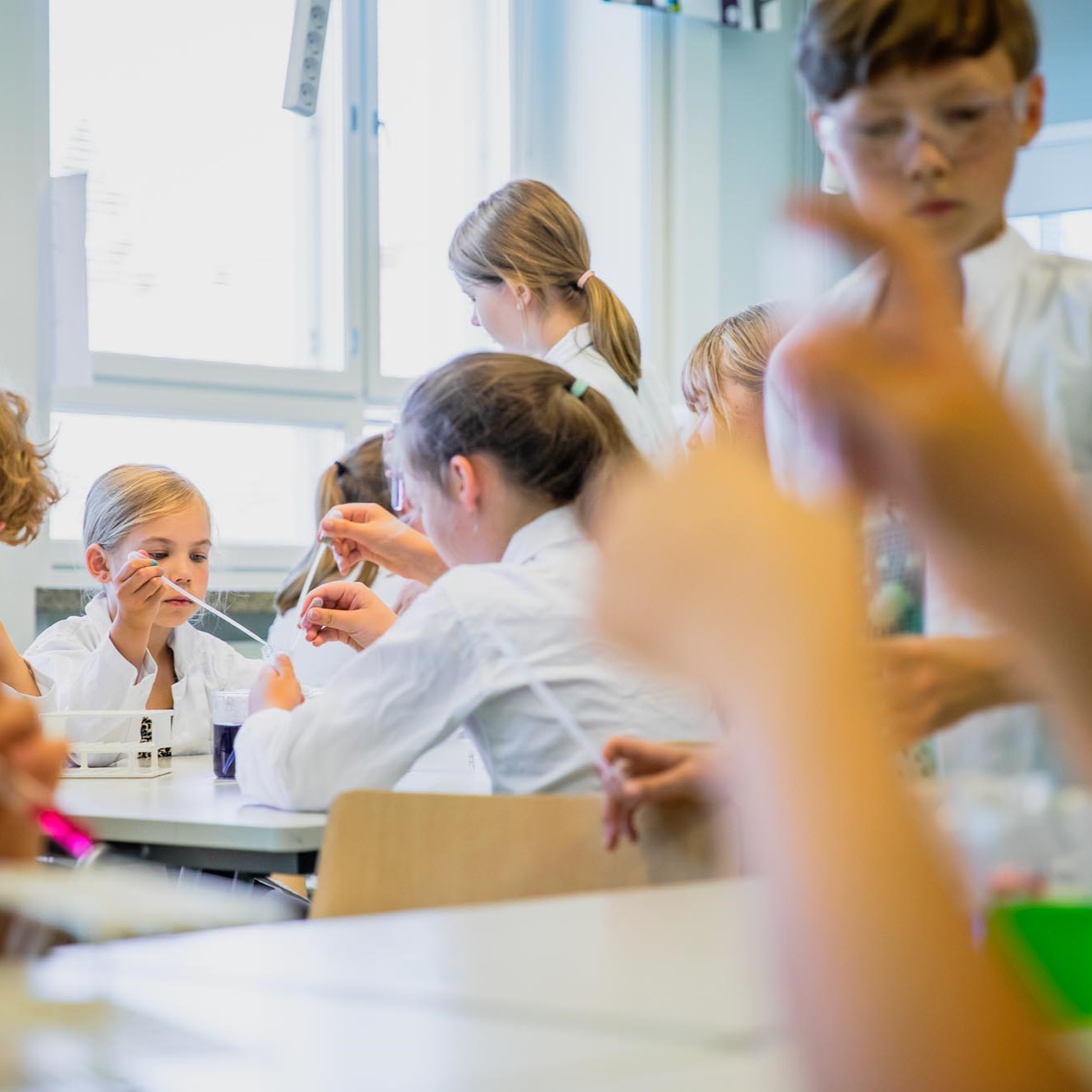 Koulun oppilaita tekemässä kemiallisia kokeita luokassa.
