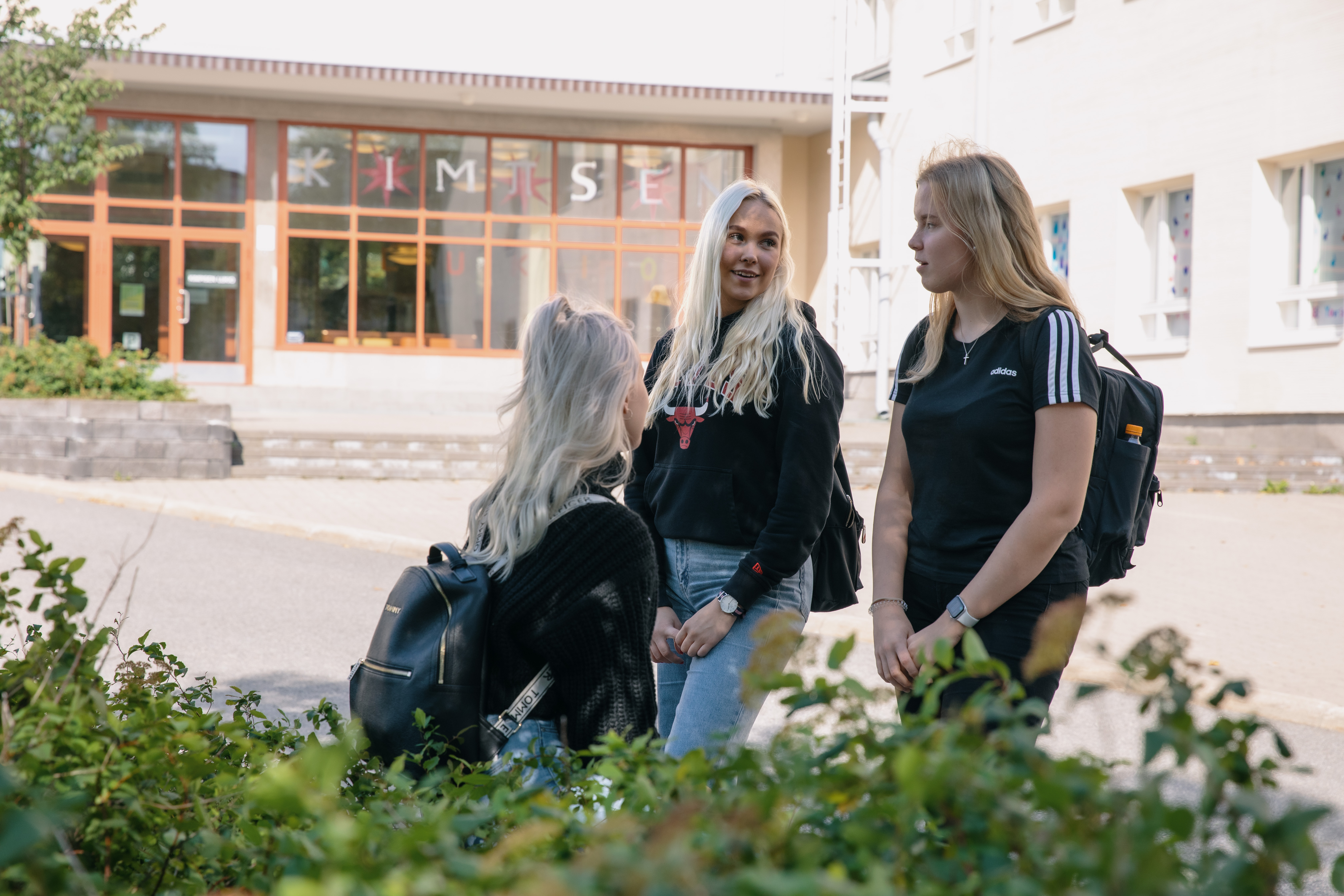 Kolme opiskelijaa lukion pihalla.