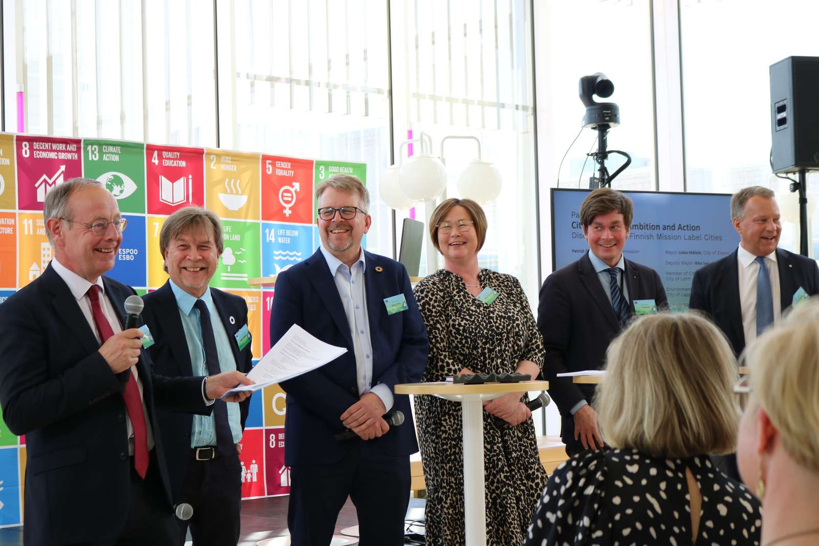 Six people on the stage smiling to each other.