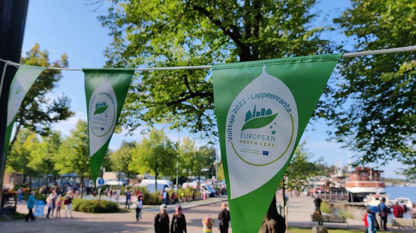 Etualalla vihreät viirit. Taustalla Lappeenrannan satama ja ihmisiä.