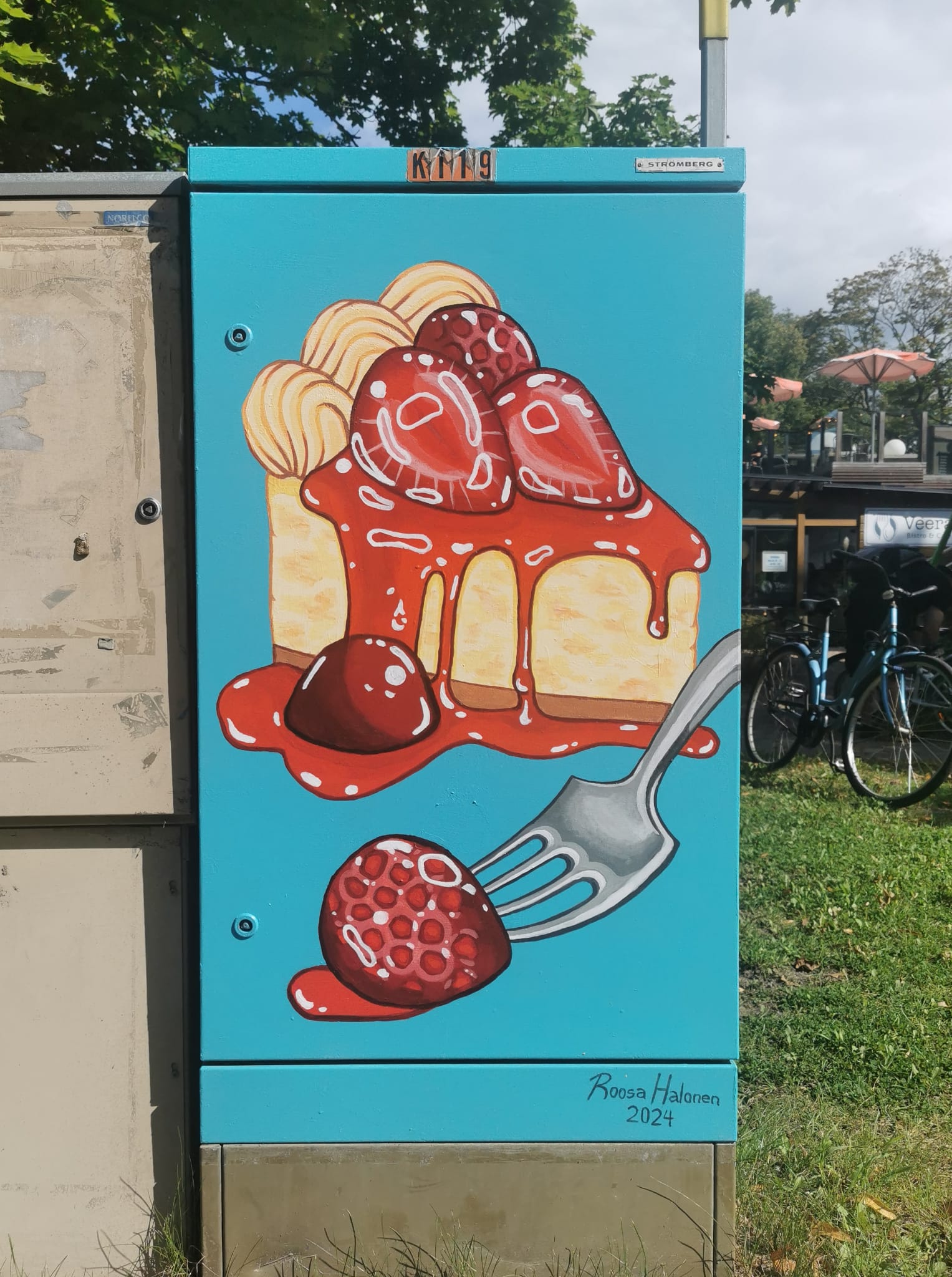 Jakokaappi on maalattu siniseksi ja siihen on toteutettu maalaamalla teos, joka muistuttaa mansikkajuustokakkua.