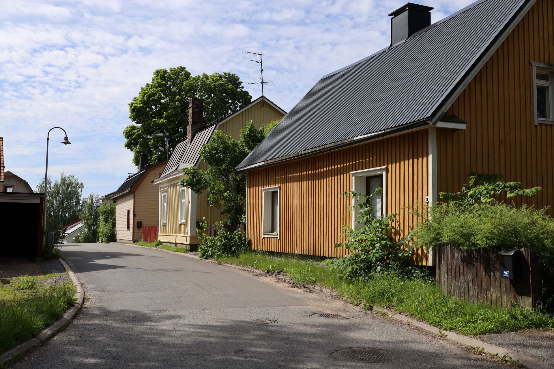 Kellertäviä vanhoja harjakattoisia taloja kapean kadun varrella.