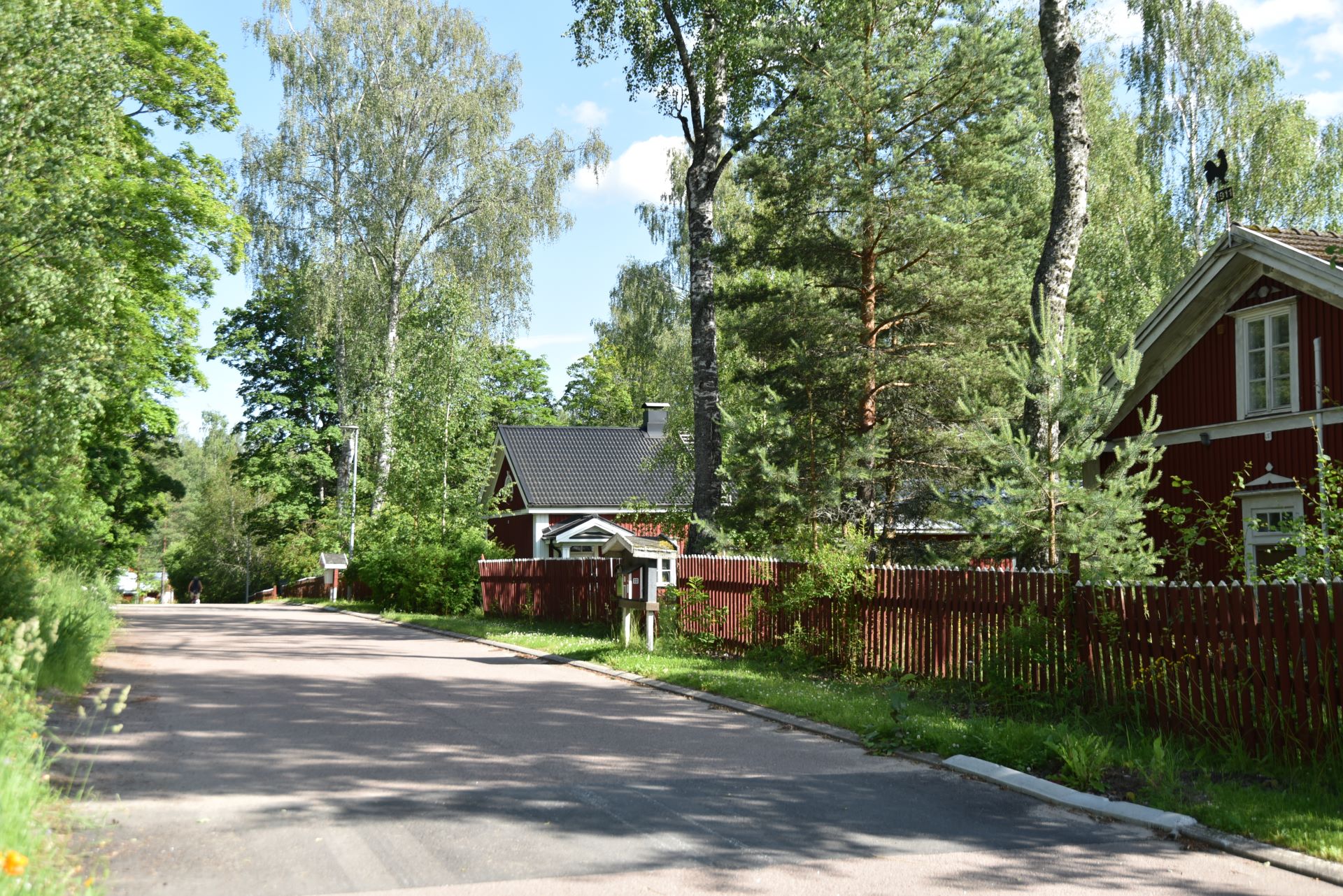 Punaisia vanhoja taloja hiekkatien varressa.