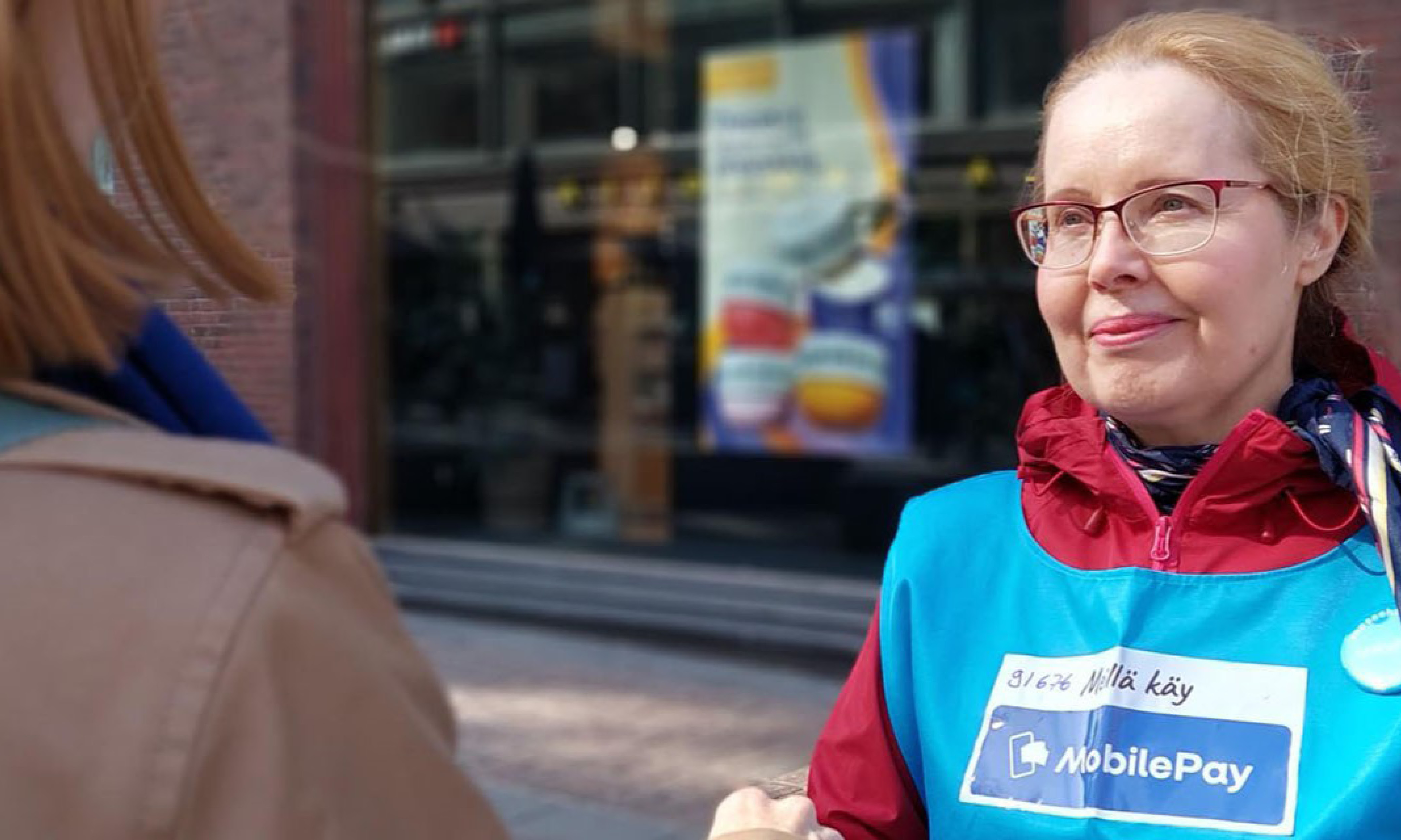 Siniliivinen UNICEF-vapaaehtoinen keräämässä lahjoituksia lippaaseen.