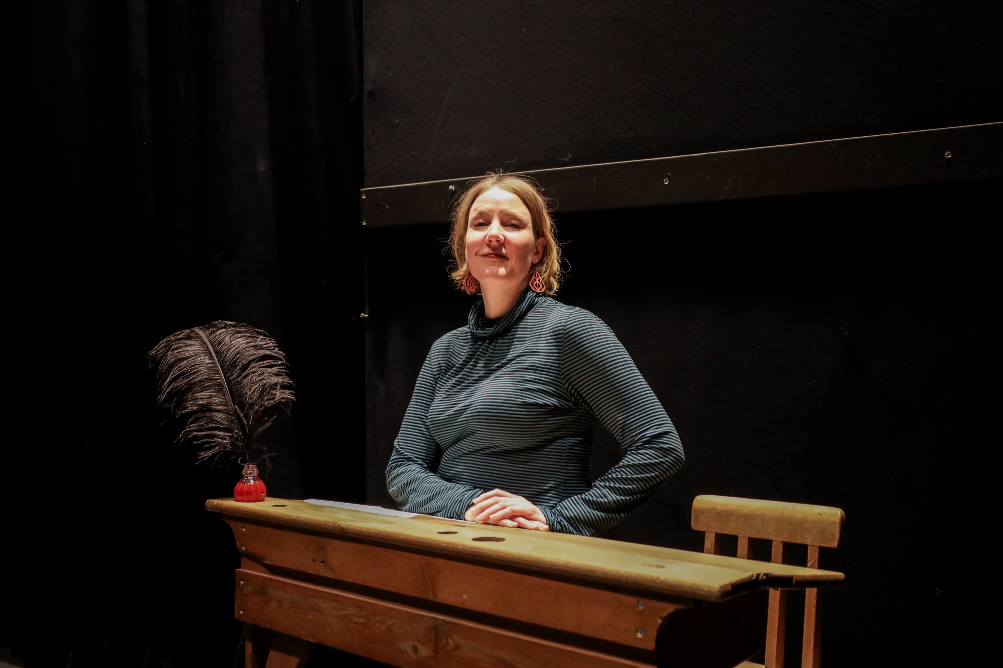 Nainen istuu vanhanaikaisen pulpetin ääressä. 