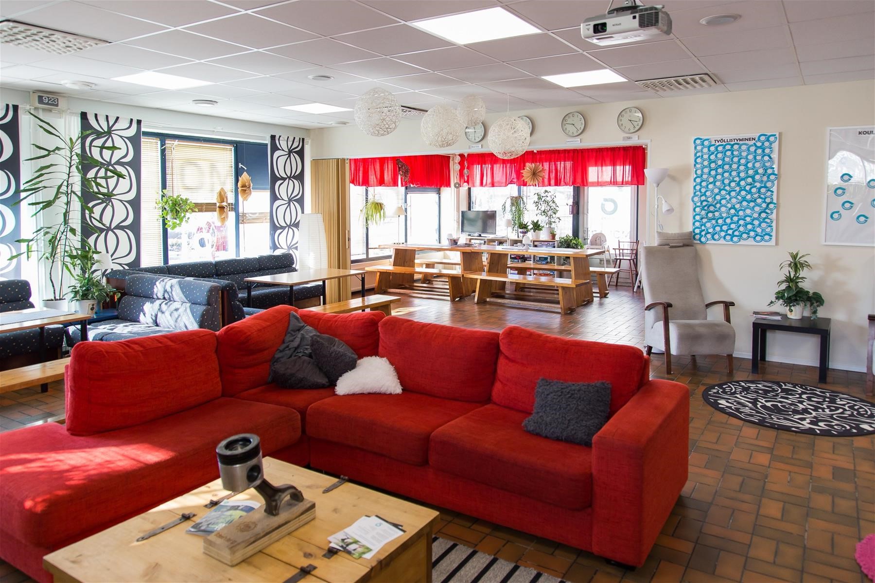 Nuorisotilan oleskelutilaa, jossa sohvaryhmiä, taustalla keittiötilan pirttikalusto.