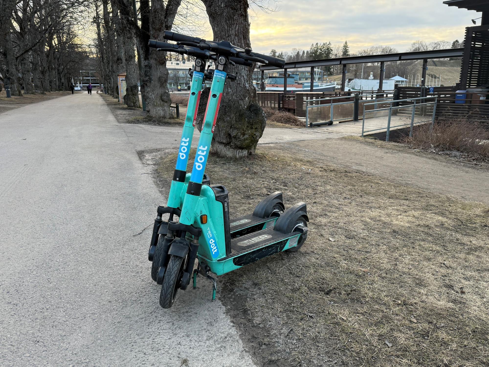 Kaksi sähköpotkulautaa kasinonpuistossa kevyenliikenteenväylän laidalla.