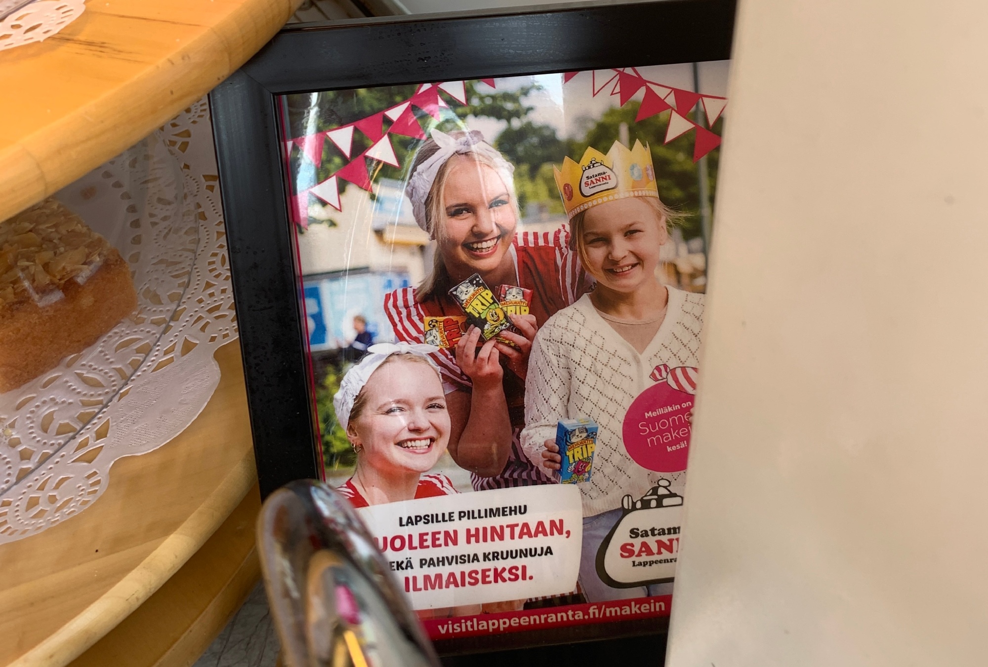 Kuva kehyksissä olevasta mainoksesta, jossa kaksi hymyilevää lasta ja aikuinen