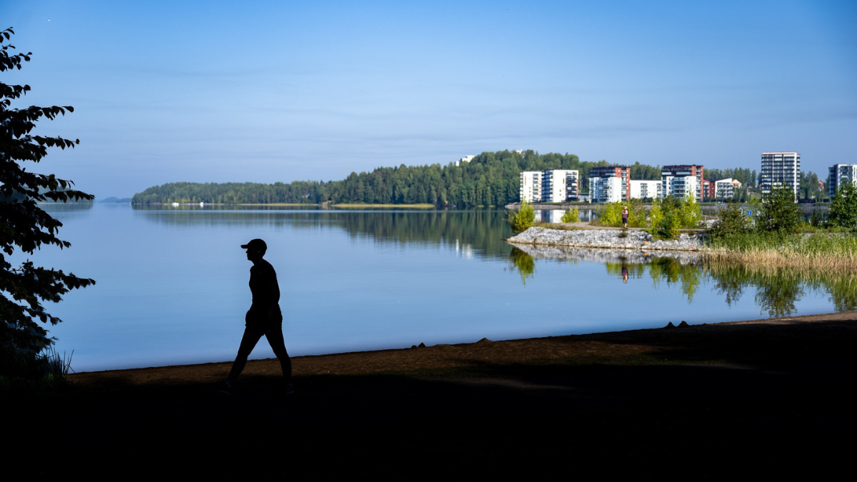 Henkilö kävelee rannalla. Taustalla järvimaisema.
