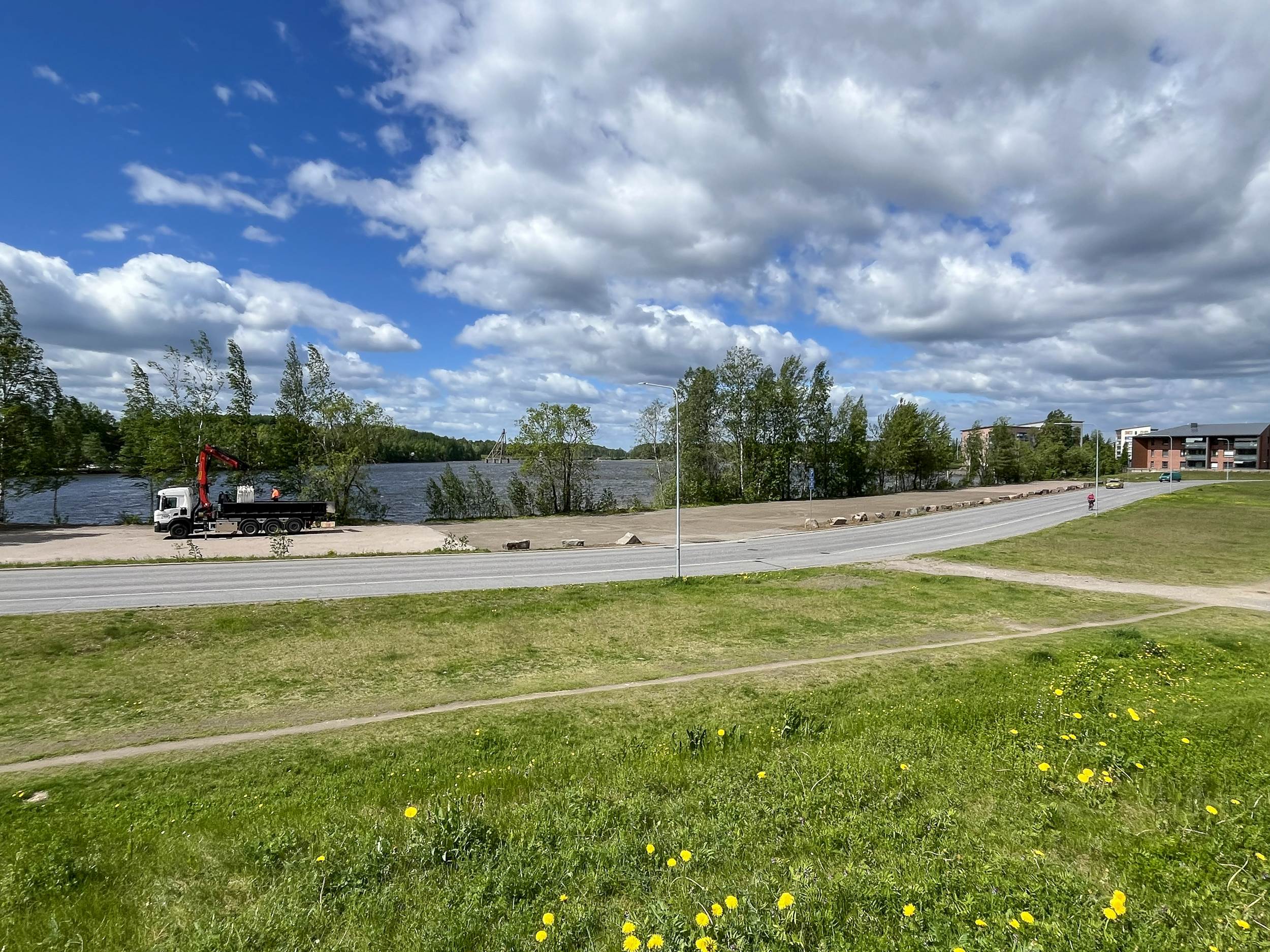 Parkkipaikan rakentamista Saimaan äärellä. Tie ja vihreää nurmikkomaastoa.