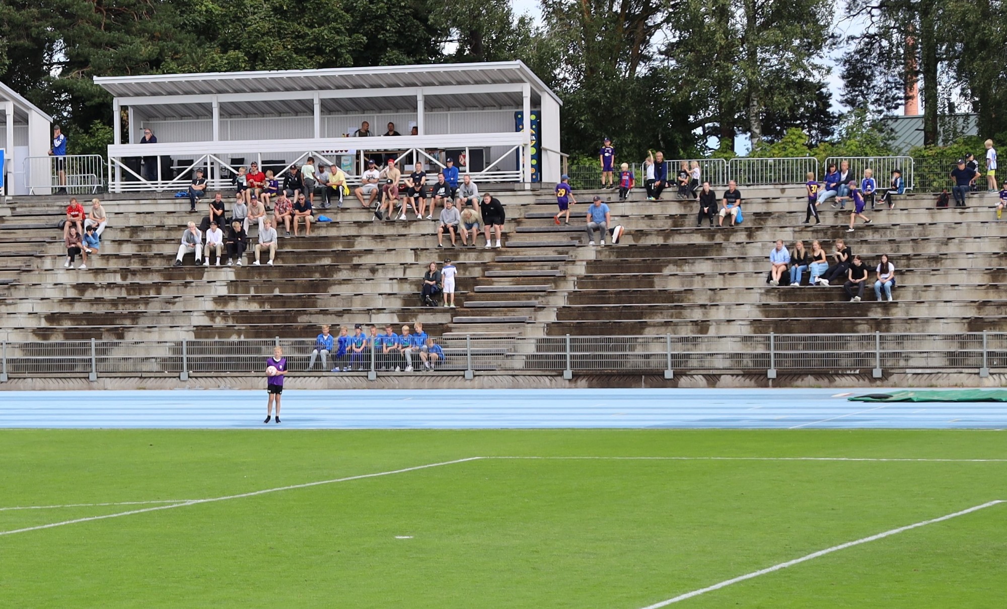 Kimpisen stadionin nurmikenttä, jonka taustalla yleisöä katsomossa seuraamassa ottelua.