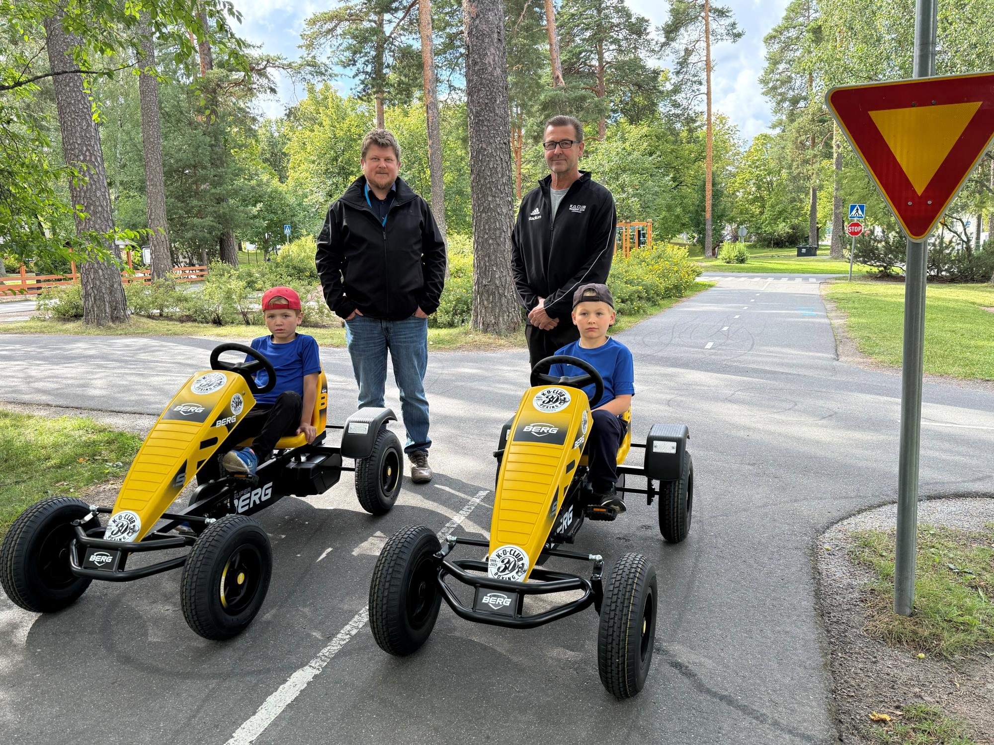 Topi Kangas, Mika Riikonen sekä testikuljettajat Väinö ja Viljo esittelemässä lahjoitettuja polkuautoja liikennepuistossa.