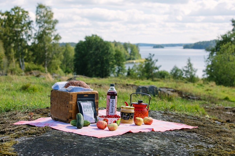 Kuvassa piknik-kori järvimaisemassa