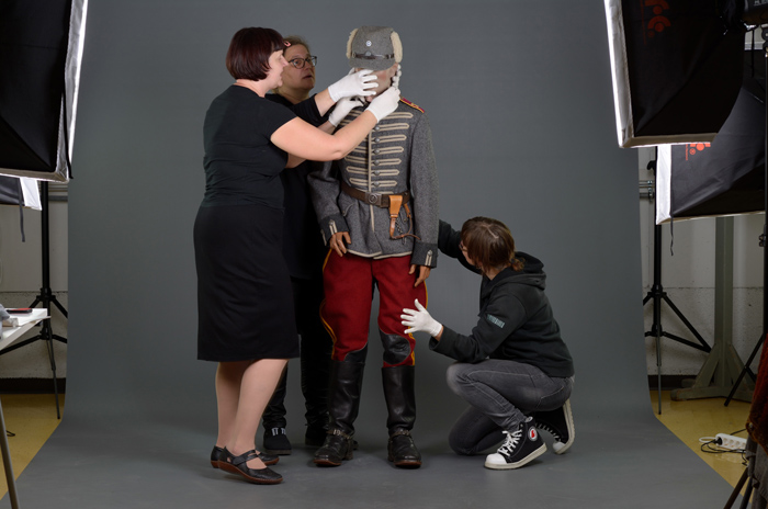 Museon kokoelmatyöntekijät asettelevat mallinuken ylle 1920-ja 30-luvuilla käytettyä ratsuväen asepukua. 