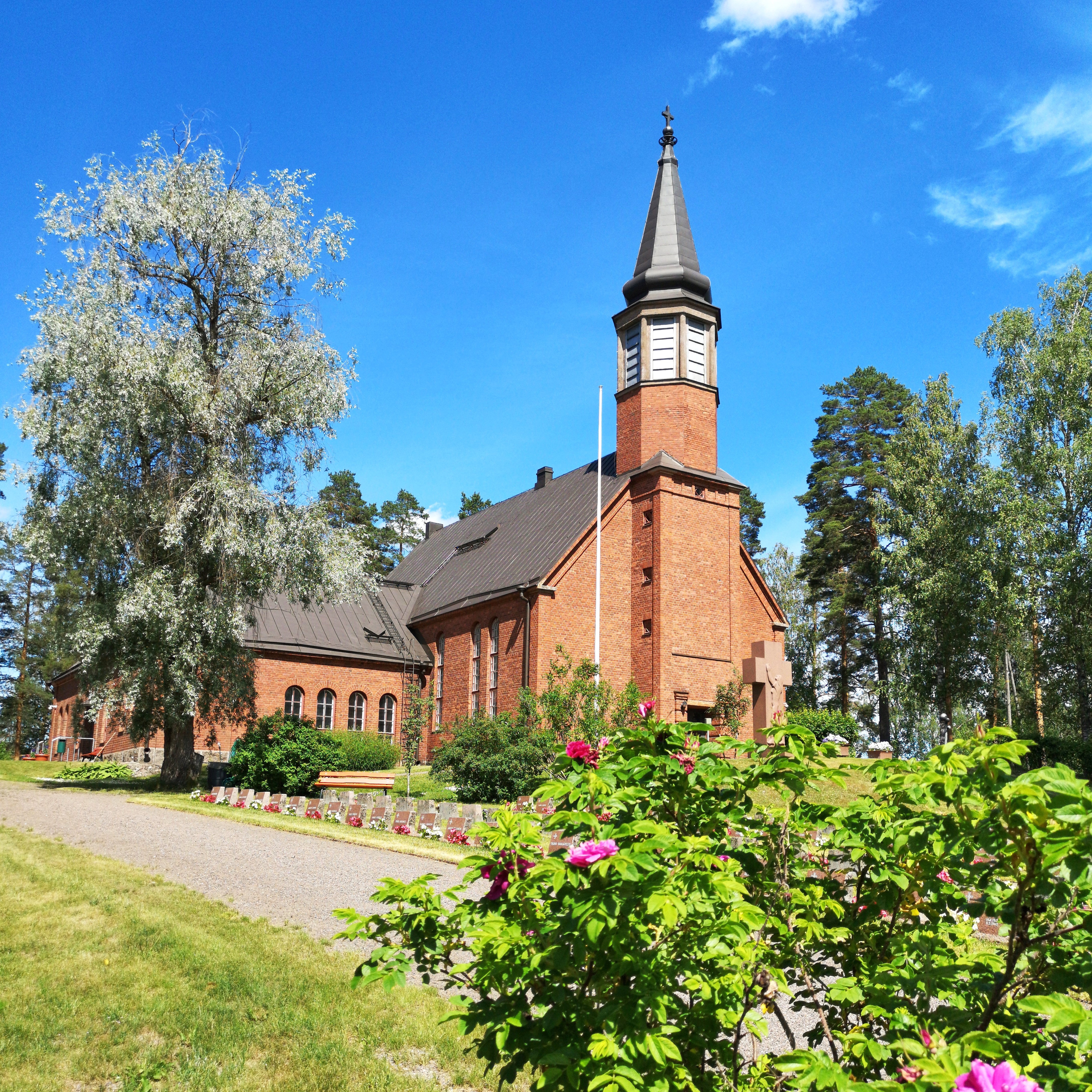 Punatiilinen kirkko ja metsää.