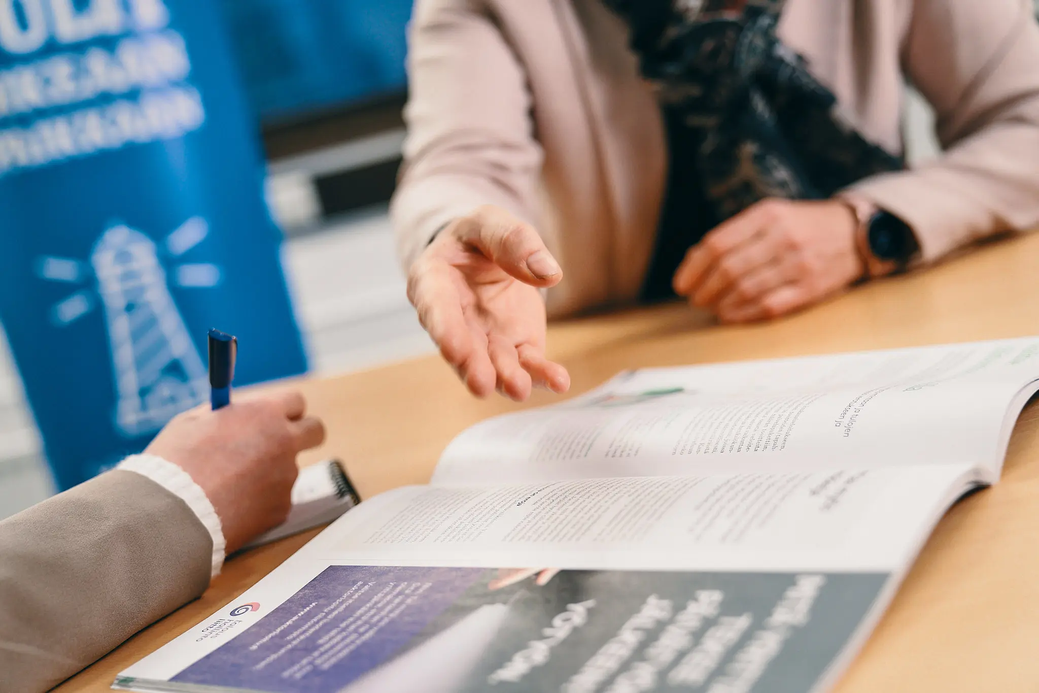 neuvoja esittelee mainoslehteä asiakkaalle