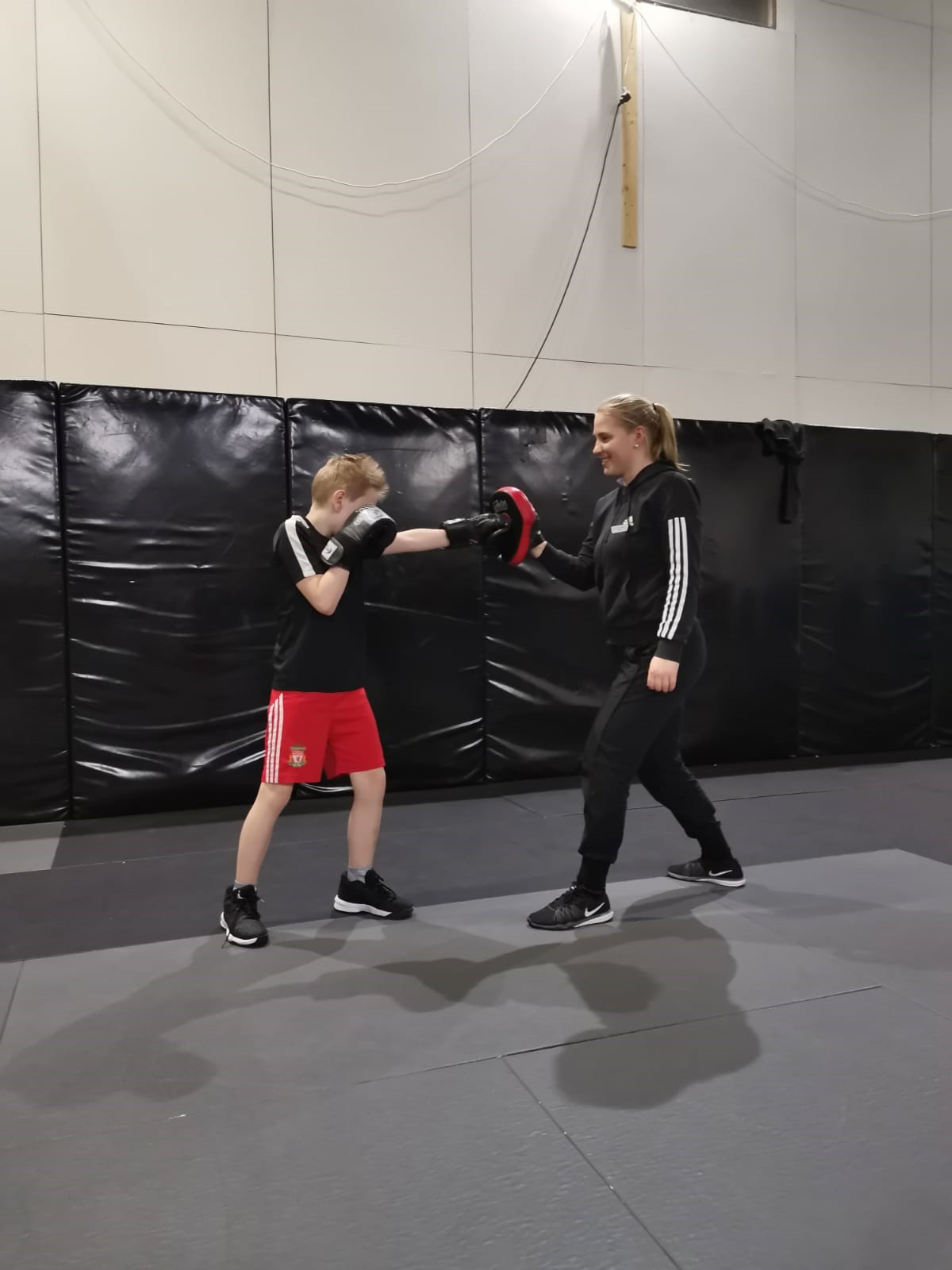 Kuva, jossa poika harjoittelee nyrkkeilyä Valttina toimivan nuoren naisen kanssa